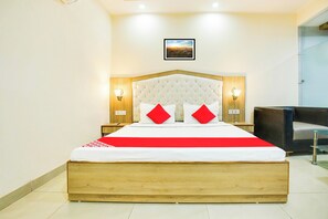 A hotel room with a large bed, two bedside lamps, a framed picture on the wall, and a chair in the corner.