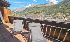 En balkon med to stole, der kigger ud over en bjerglandsby.