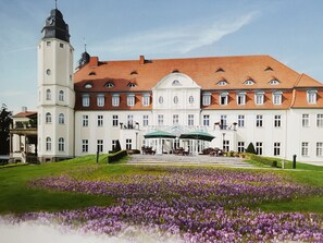 A large building with a symmetrical facade, a central entrance with a canopy, and a tower on the left. - Holiday Home With 3 Bedrooms (Goehren-Lebbin)