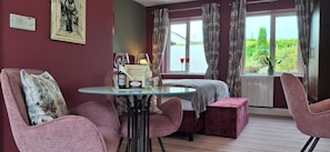 A room with a glass table, two chairs, a bed, a window with curtains, and a sign on the wall. - Stoneywood Haven (Clarinbridge)