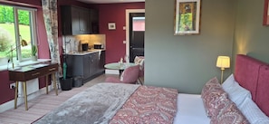 A bedroom with a bed, bedside table, lamp, and a view of the kitchen. - Stoneywood Haven (Clarinbridge)