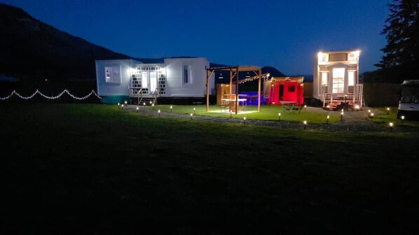 A series of cabins with attached porches, surrounded by a landscaped area with small lights.