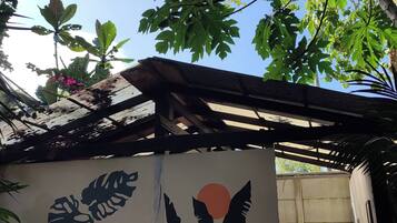A room with a mural of leaves and a sun, a fan, and a washing machine.