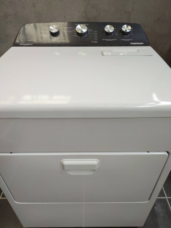 Una lavadora Whirlpool con puerta frontal y panel de control con múltiples perillas.