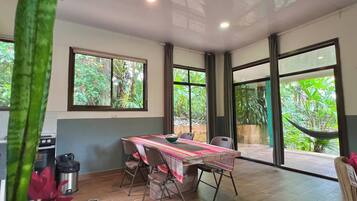 Amplia habitación con una mesa de comedor, sillas y ventanas grandes que ofrecen vista a zonas verdes.