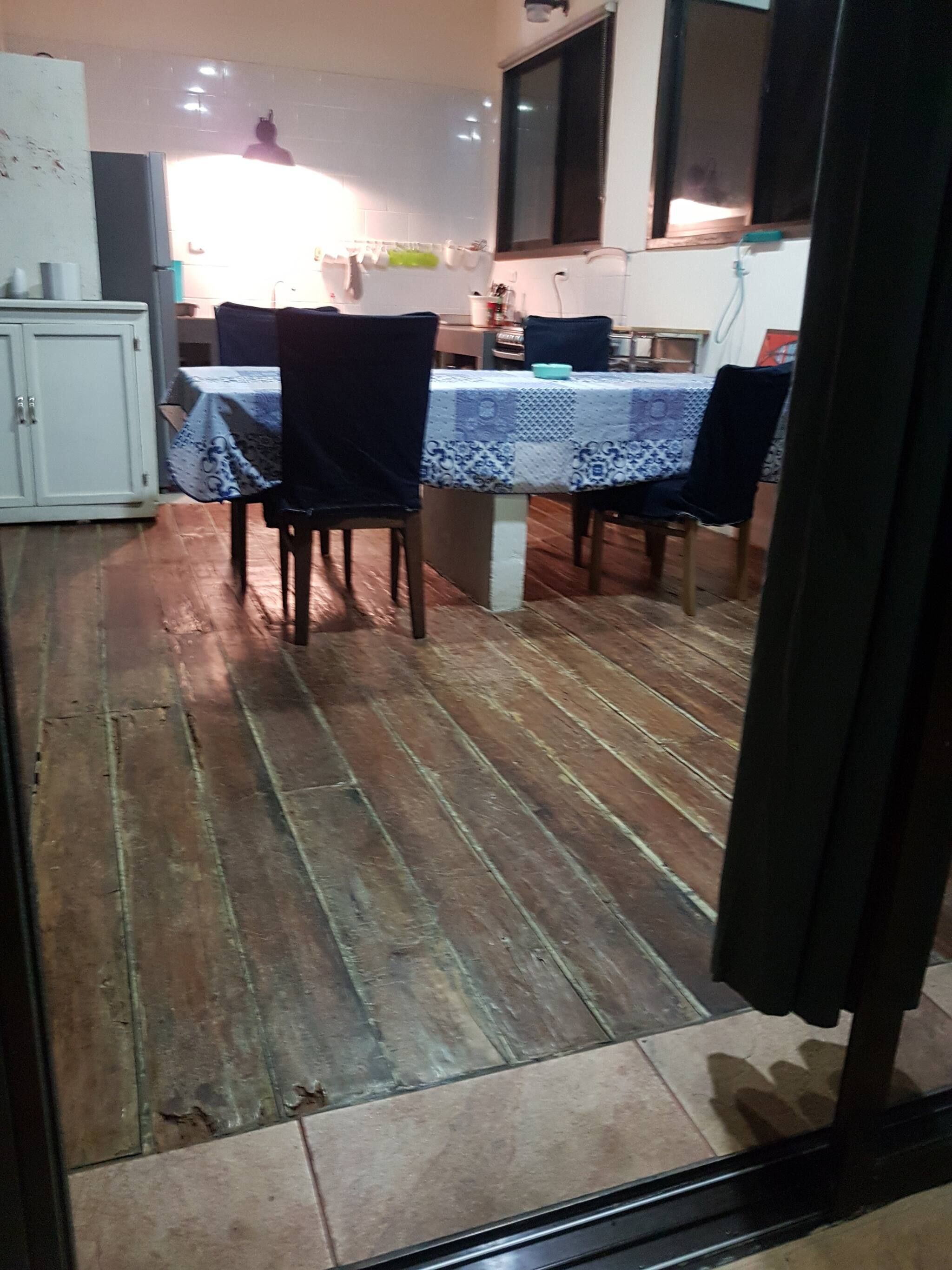 A dining area with a table set for four, a kitchen in the background, and a tiled floor.