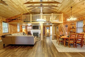 A spacious cabin interior with a loft bedroom, a dining area, and a fireplace. - Old Forge Winter Escape: Snowmobile & Ski! (Old Forge)