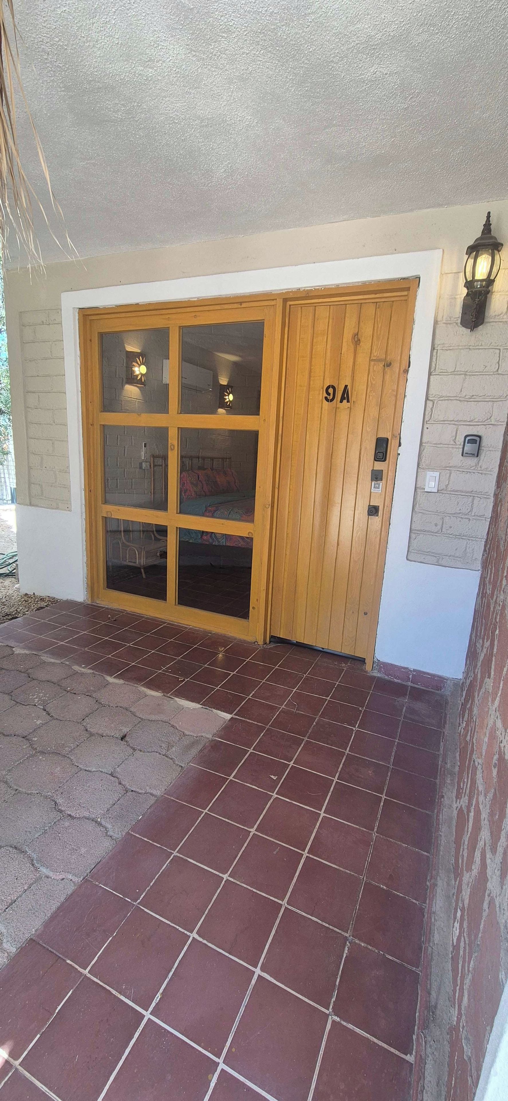 Una puerta de madera con paneles de vidrio y el número '9A' grabado.