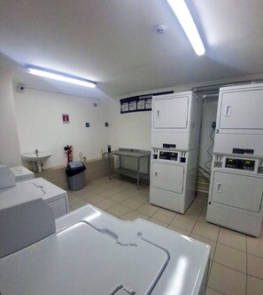 A laundry room with stacked washing machines, a sink, and a fire extinguisher.