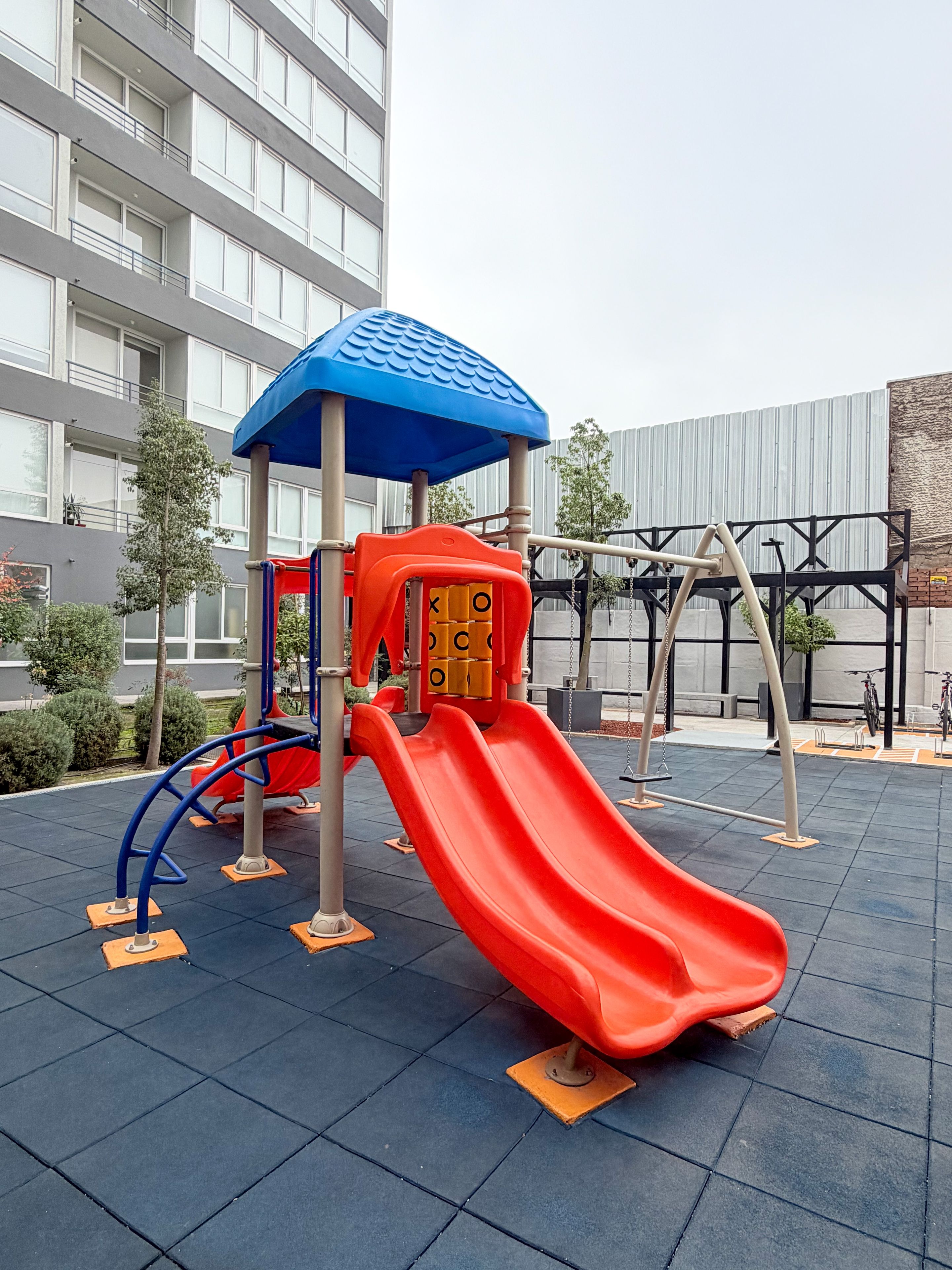 A playground with a red slide and a blue-roofed play structure.