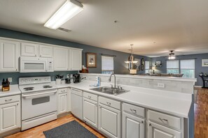 A modern kitchen with white cabinetry, a built-in oven, a microwave, and a stainless steel sink. - Golf + Pool Fun! Family Condo 6 Mi to Myrtle Beach (Myrtle Beach)