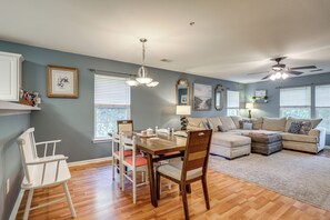 A spacious living room with a dining area, a ceiling fan, and a large window providing natural light. - Golf + Pool Fun! Family Condo 6 Mi to Myrtle Beach (Myrtle Beach)
