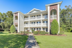 A multi-story building with a central courtyard, balconies, and a well-maintained lawn. - Golf + Pool Fun! Family Condo 6 Mi to Myrtle Beach (Myrtle Beach)