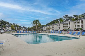 A swimming pool surrounded by lounge chairs and a white fence, with multi-story buildings in the background. - Golf + Pool Fun! Family Condo 6 Mi to Myrtle Beach (Myrtle Beach)
