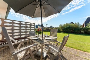 An outdoor dining area with a table, chairs, and an umbrella. - Christof House, Apartment 2: Seehund (Wenningstedt-Braderup (Sylt))
