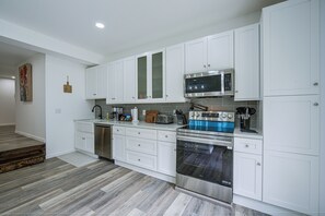A modern kitchen with white cabinetry, stainless steel appliances, and a herringbone wood floor. - Great for Groups! Spacious Milroy Escape (Milroy)
