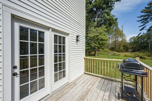 A wooden deck with a barbecue grill, a white door with glass panels, and a view of a green landscape with trees. - Great for Groups! Spacious Milroy Escape (Milroy)