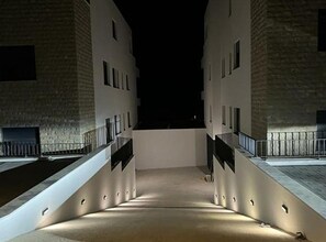 A nighttime view of a building with a central open space, flanked by two wings with balconies. - Retro Luxury Swim & Stay Apartment (Murter-Kornati)