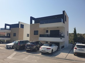 A modern multi-story residential building with a parking lot. - Retro Luxury Swim & Stay Apartment (Murter-Kornati)