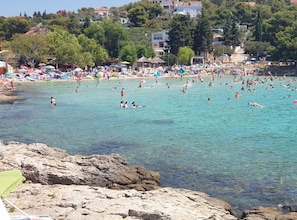 A coastal area with clear water, rocky shoreline, and a densely populated beach with people swimming and sunbathing. - Retro Luxury Swim & Stay Apartment (Murter-Kornati)
