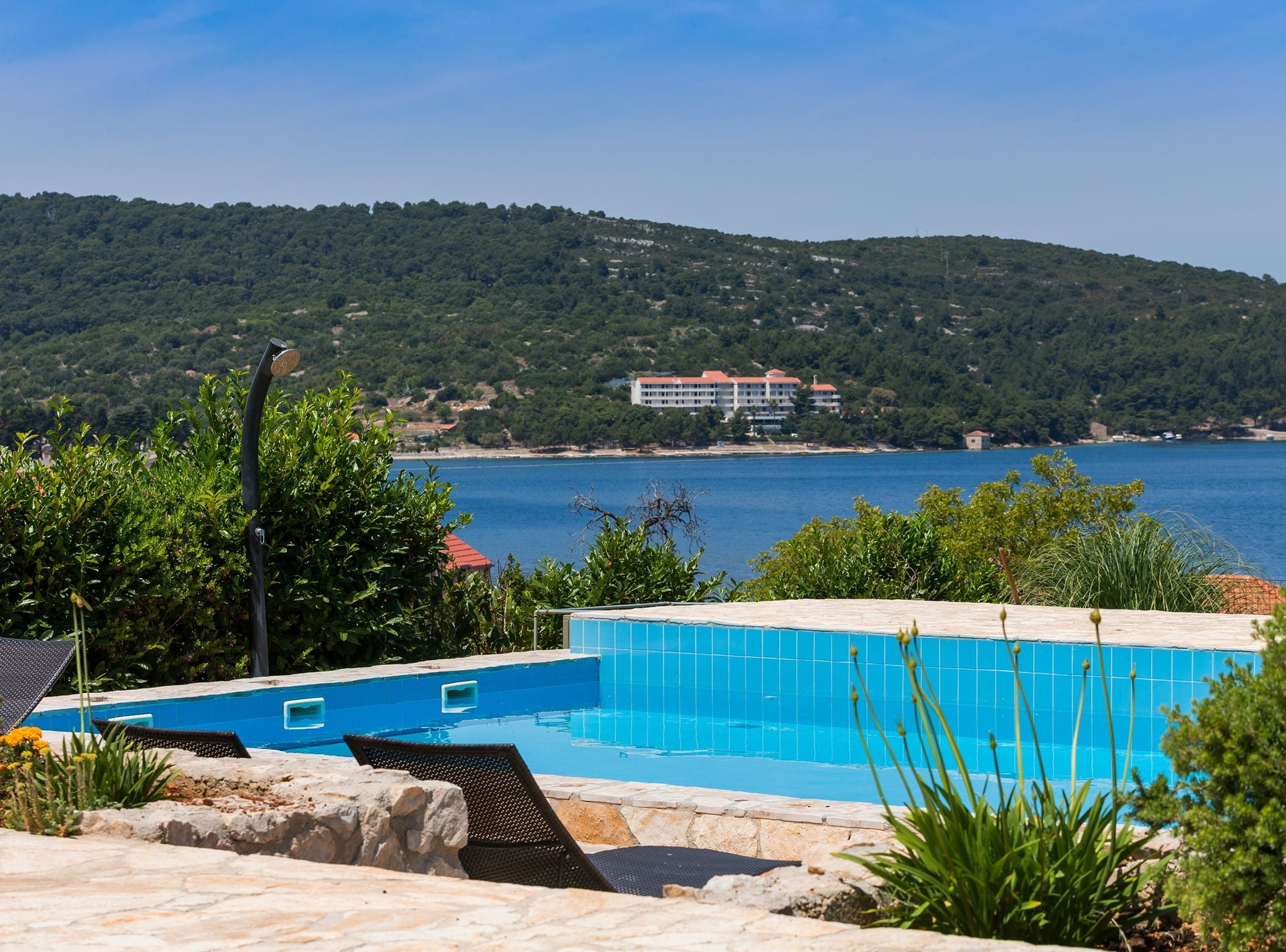 A swimming pool with a view of a body of water and a hillside in the background.