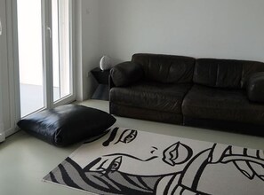A living room with a brown leather sofa, a black cushion, and a patterned rug. - Villas Linne (Vis)