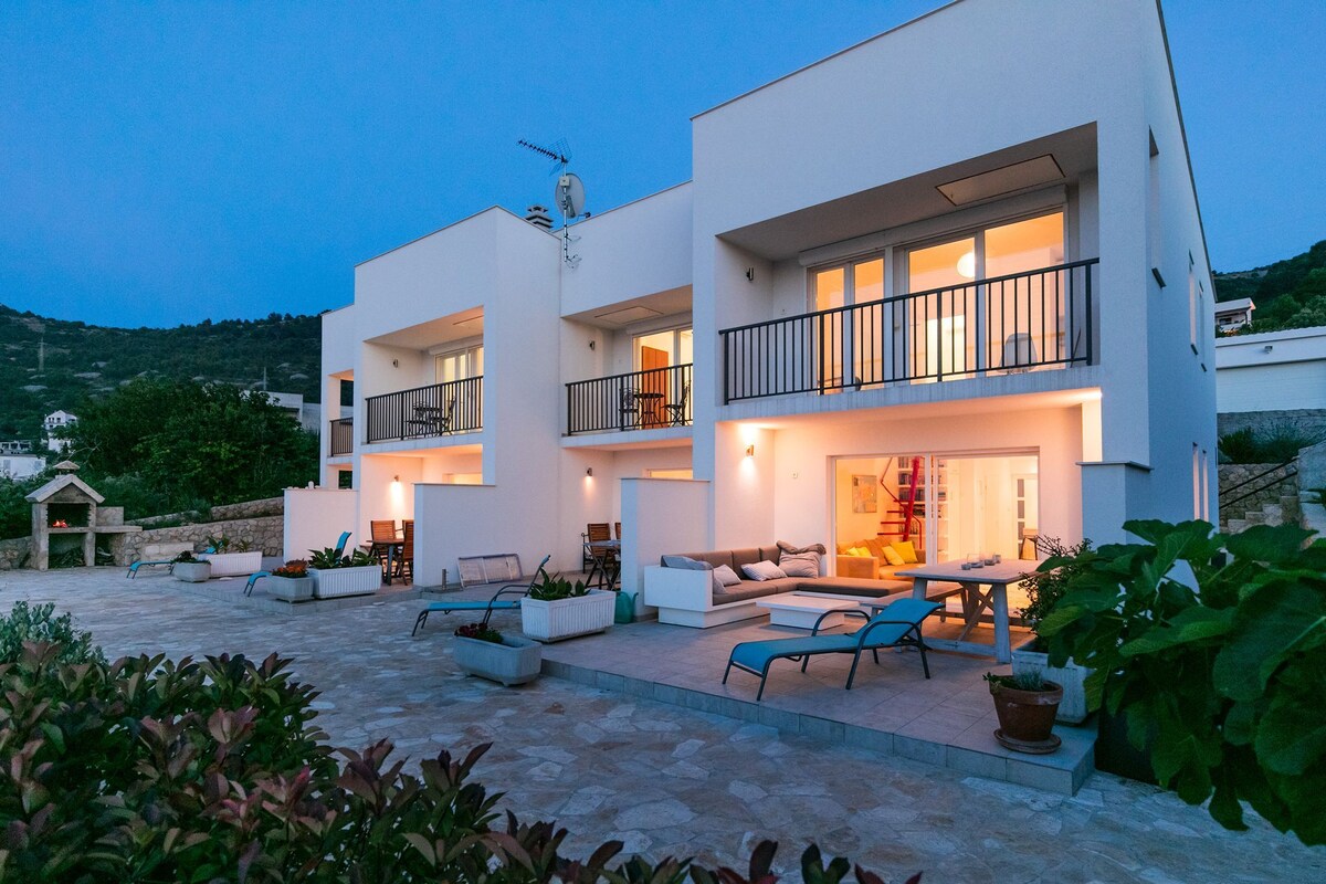 A modern two-story building with outdoor seating and a stone-paved courtyard.