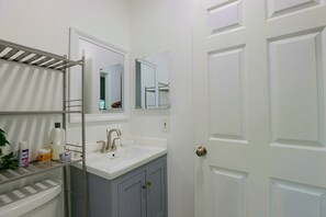 A bathroom with a white sink, a mirror, a towel rack, and a door. - 2 Mi to Universal Orlando! Quiet Studio Suite (Orlando)