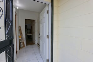 A hallway with a white door, a tiled floor, and a door handle. - 2 Mi to Universal Orlando! Quiet Studio Suite (Orlando)