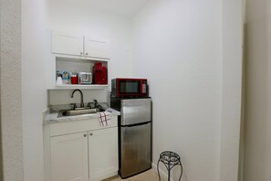 A compact kitchenette with a stainless steel refrigerator, a red microwave, a sink, and a small table. - 2 Mi to Universal Orlando! Quiet Studio Suite (Orlando)