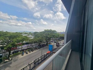 A view from a balcony overlooking a busy street with trees and parked vehicles. - 2-Bedroom Loft Condo in Boat Avenue, Phuket (Tambon Choeng Thale)