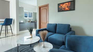 A modern living room with a blue sofa, a round coffee table, and a painting on the wall.