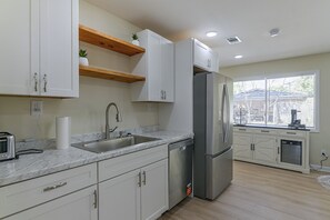 A modern kitchen with white cabinets, a stainless steel refrigerator, and a window providing natural light. - 2 Mi to MSU Campus: Starkville 4BR Home (Starkville)