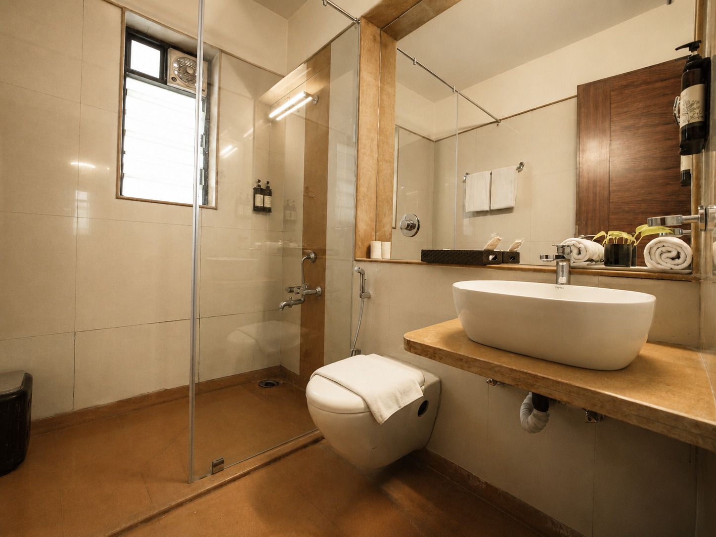 A modern bathroom with a glass-enclosed shower, a white sink, and a wooden vanity.