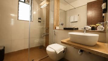 A modern bathroom with a glass-enclosed shower, a white sink, and a wooden vanity.