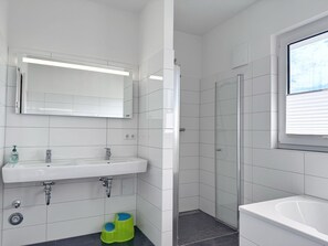 A modern bathroom with a white sink, mirror, and shower. - Three-Bedroom Vacation Apartment Near the Beach - Mein Glowe - 1st Floor, Left (Glowe)