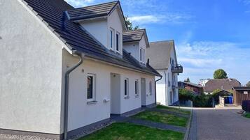 A residential building with a sloped roof, a paved driveway, and a well-maintained lawn.