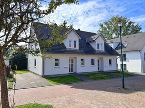 A two-story residential building with a paved driveway and a small lawn area. - Modern three-bedroom semi-detached home with a fireplace - Mein Glowe - DHH Rechts (Glowe)