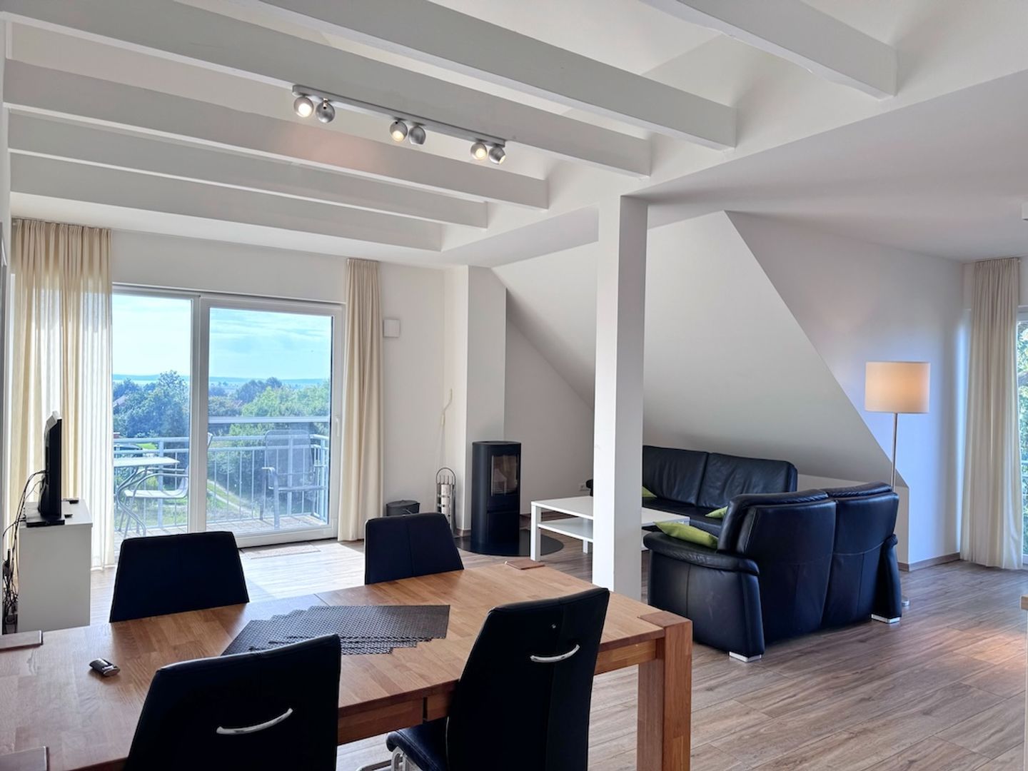 A modern living room with a dining area, a fireplace, and a large window with a view.