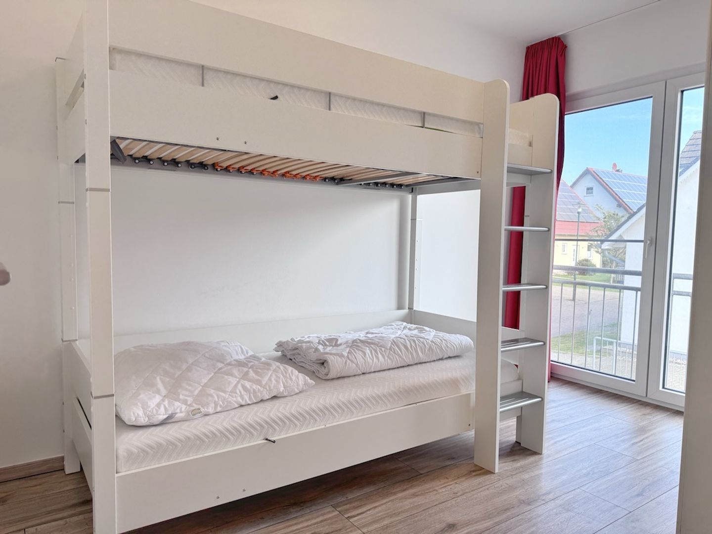 A bunk bed with a pull-out desk in a room with a large window.