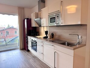 A modern kitchen with a built-in oven, microwave, and stainless steel sink. - Three-Bedroom Vacation Apartment Near the Beach - Mein Glowe - 1st Floor, Right (Glowe)