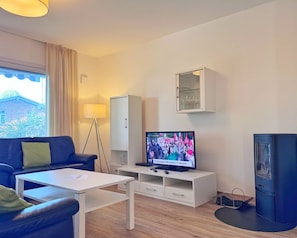 Ein modernes Wohnzimmer mit einer Couch, einem Couchtisch, einem Fernseher, einem Schrank und einer Vitrine.
