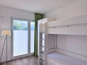 Ein Zimmer mit einem Etagenbett, einer Stehlampe und einem Fenster mit Jalousien.
