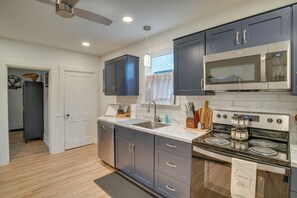 A modern kitchen with dark cabinets, a stainless steel microwave, and a stove. - Walk to Downtown Plymouth Retreat w/ Fire Pit (Plymouth)