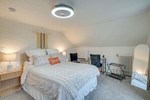 Ein Schlafzimmer mit einem großen Bett, einem Nachttisch, einer Lampe, einem Sessel, einer Heizung und einer Deckenleuchte.