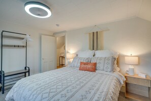 A bedroom with a bed, bedside lamps, a hanging light fixture, a wardrobe, and a door leading to another room. - Walk to Downtown Plymouth Retreat w/ Fire Pit (Plymouth)