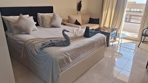 A hotel room with a bed, a sofa, a small table, and a view of the outside. - Luxurious Studio with Ocean View in Hurghada, Red Sea (Red Sea Governorate)