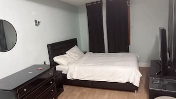 A bedroom with a bed, a dresser, a television, and a mirror.