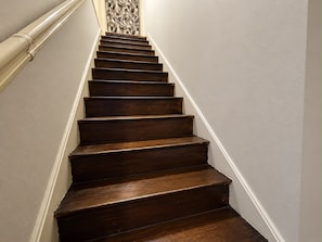 A wooden staircase with white walls and a decorative wall panel at the top.