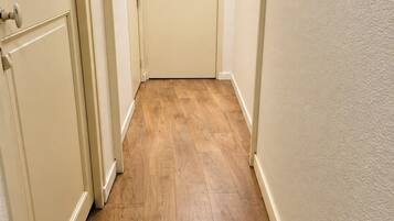 A hallway with wooden flooring and cream-colored walls.